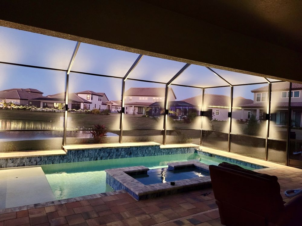 Pool cage with warm white LED sconces at dusk overlooking lake in Tampa Bay