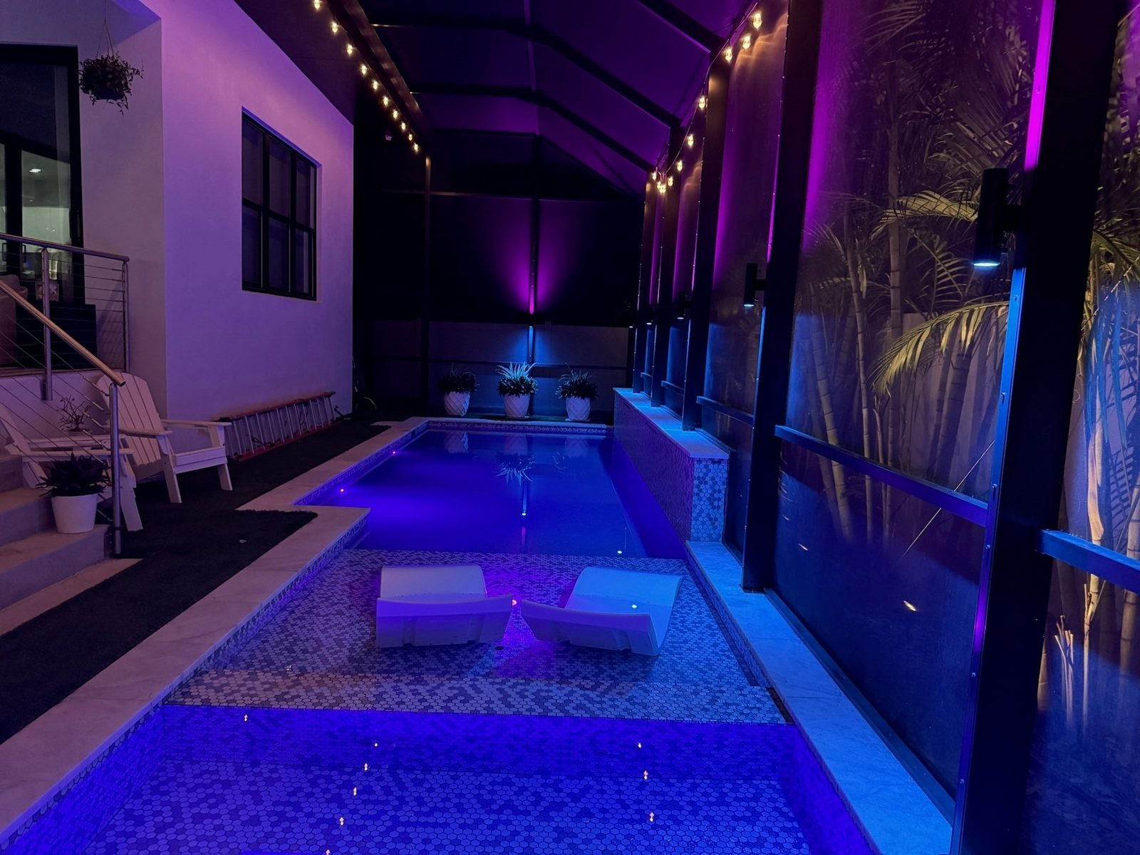 Custom LED pool cage lighting at night in Tampa Bay with purple ambient sconces and string lights