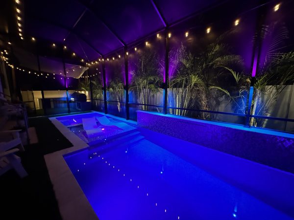 Pool cage with purple and blue ambient LED sconce lighting in Tampa