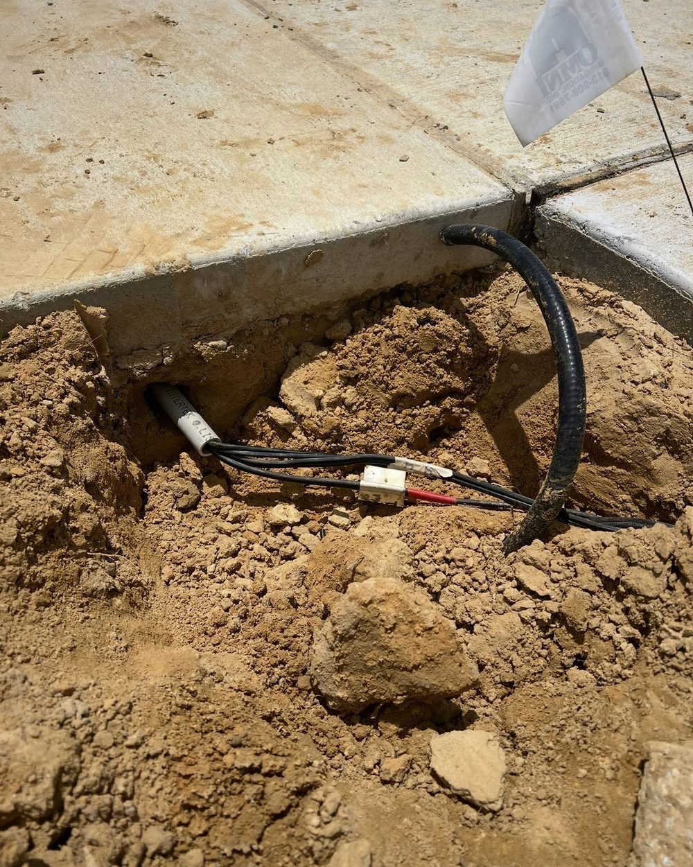 Damaged low-voltage landscape lighting wire with exposed splices dug up for repair at a Tampa Bay home
